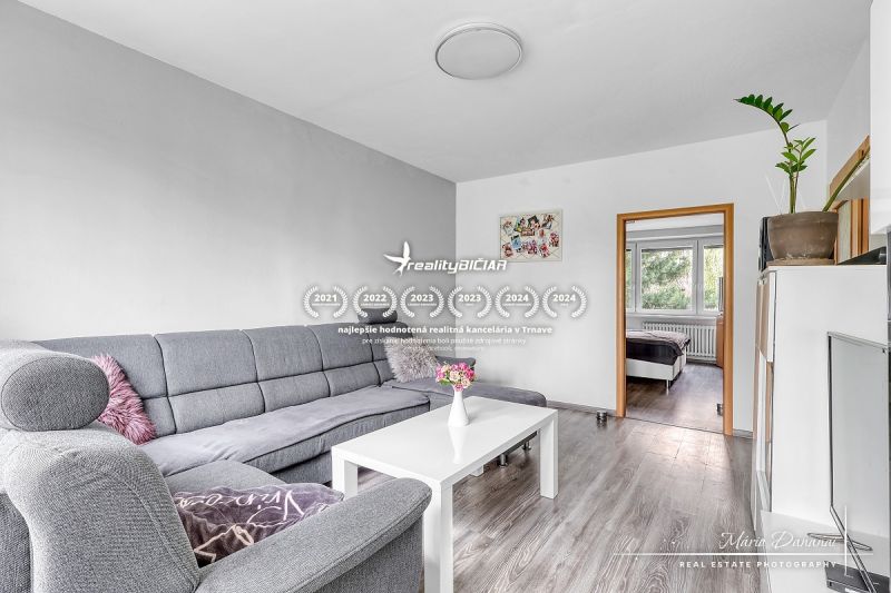 Wohnzimmer mit Ecksofa und Holzboden in einer Zweizimmerwohnung.