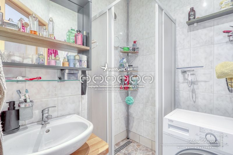 Badezimmer in einer 2-Zimmer-Wohnung mit Dusche, Waschbecken und Waschmaschine.