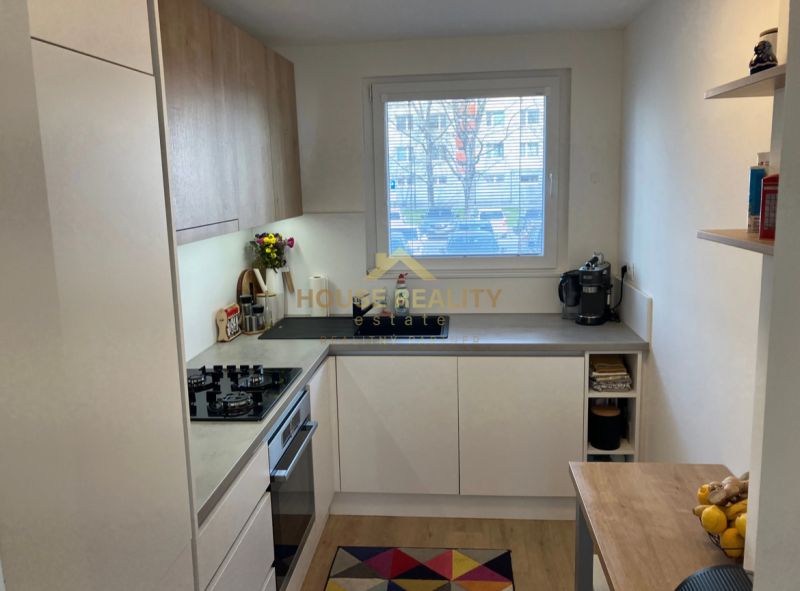 Küche in einer 3-Zimmer-Wohnung mit Holzboden und großem Fenster.