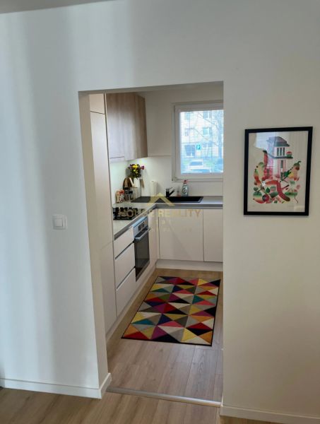 Kleine Küche mit buntem Teppich und Holzboden in einer 3-Zimmer-Wohnung.