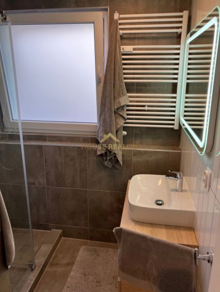 Badezimmer in einer 3-Zimmer-Wohnung mit Waschbecken, Dusche und Handtuchheizkörper.
