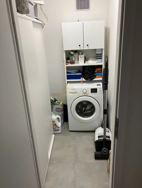 Waschküche mit Waschmaschine und Aufbewahrungsschränken in einer 3-Zimmer-Wohnung.