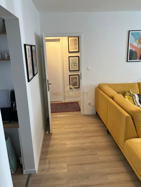 Heller Boden mit Holzdekor und gelbes Sofa in einer 3-Zimmer-Wohnung.