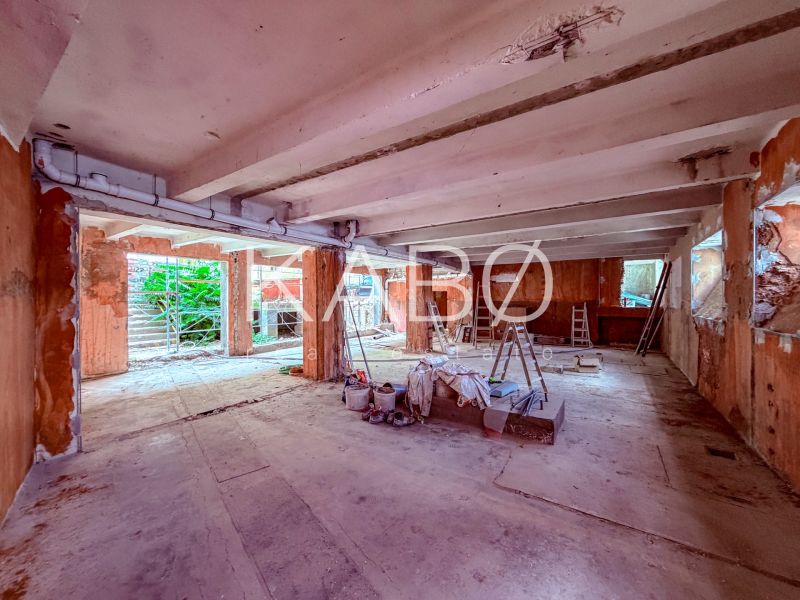 Unvollendete Geschäftsräume mit Betonboden, Leitern und Baumaterial.
