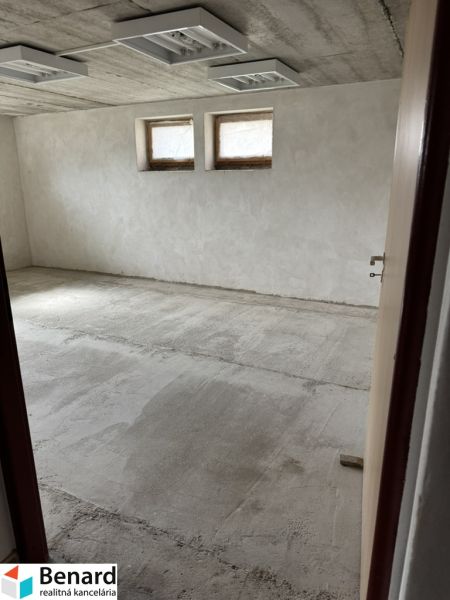 Ein unmöbliertes Zimmer in einem Einfamilienhaus mit zwei kleinen Fenstern und einem rohen Boden.