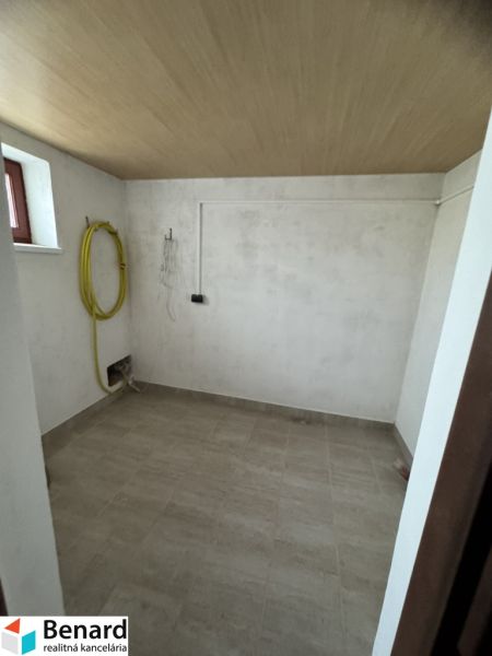 Waschküche mit gefliestem Boden und Decke mit Holzdekor in einem Einfamilienhaus.