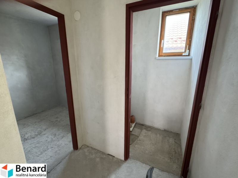 Im Einfamilienhaus befinden sich zwei Räume mit Betonboden und kleinem Fenster.