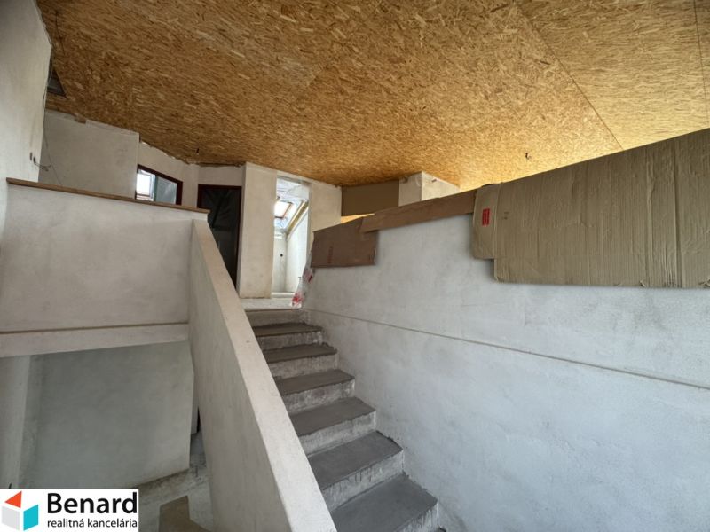 Innenraum eines Einfamilienhauses mit Treppe, weißen Wänden und OSB-Platten an der Decke.