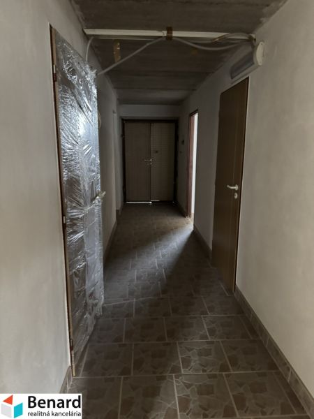 Flur in einem Einfamilienhaus mit beigefarbenen Fliesen auf dem Boden und Plastiktüren.