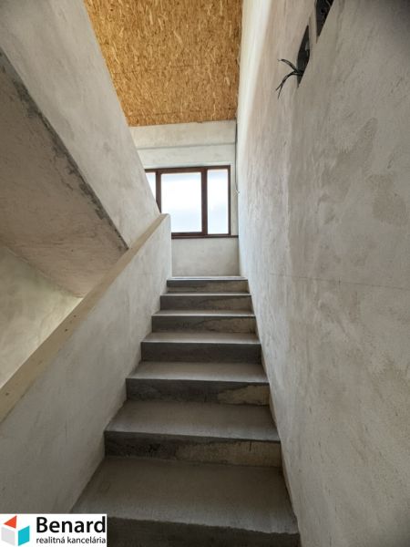 Eine Betontreppe führt zu einem Fenster, Decke aus OSB-Platten, Einfamilienhaus.