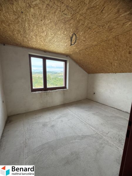 Ein Blick in einen leeren Raum eines Einfamilienhauses mit Dachfenster und Betonboden.