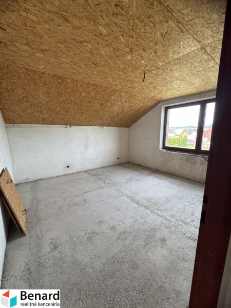 Ein Dachzimmer in einem Einfamilienhaus mit Holzbalkendecke und großem Fenster.