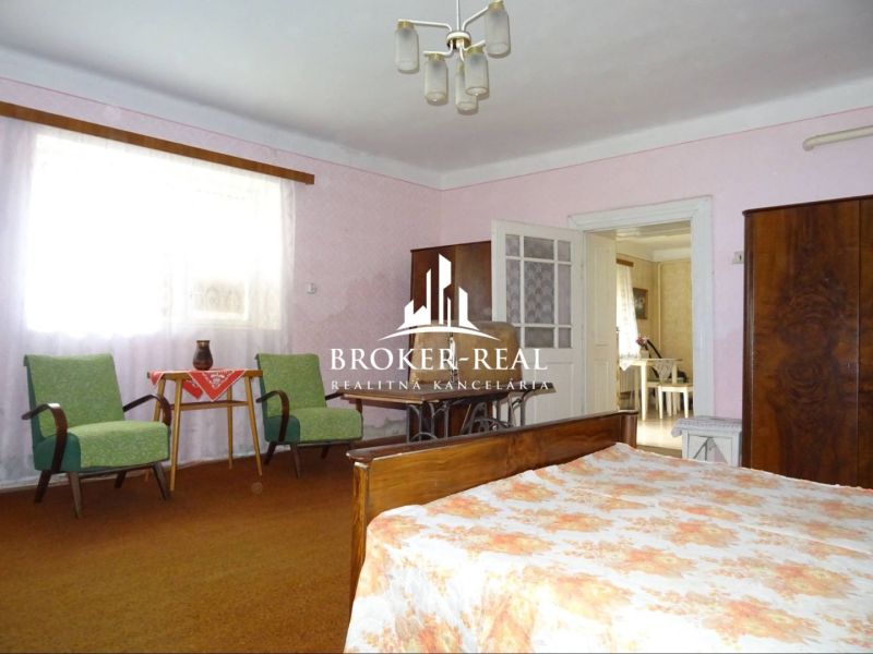 Ein Zimmer in einem Einfamilienhaus mit Möbeln und einem Bett, Boden mit Teppichdekor.