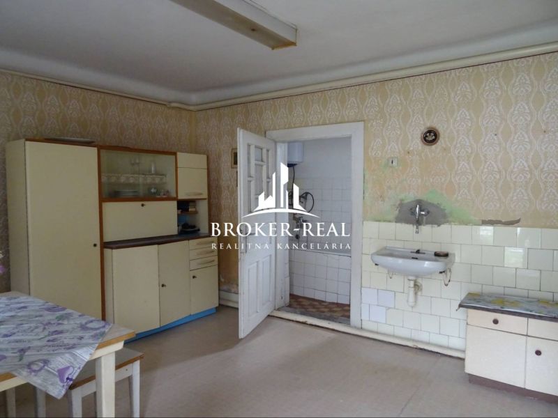 Küche in einem Einfamilienhaus mit Vintage-Möbeln und Spülbecken, Boden mit Holzdekor.