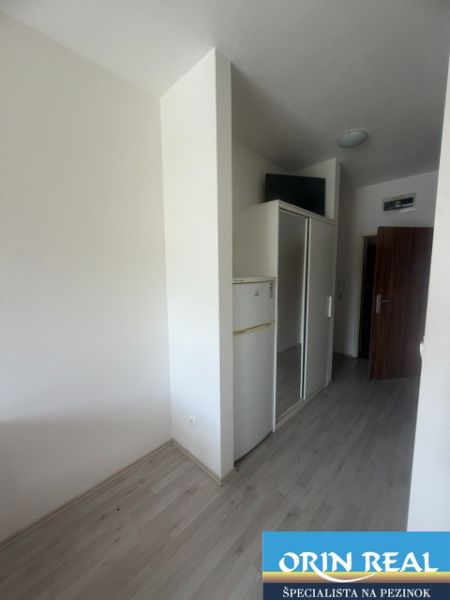 Einzimmerwohnung mit Holzboden, Kühlschrank und Einbauschrank.