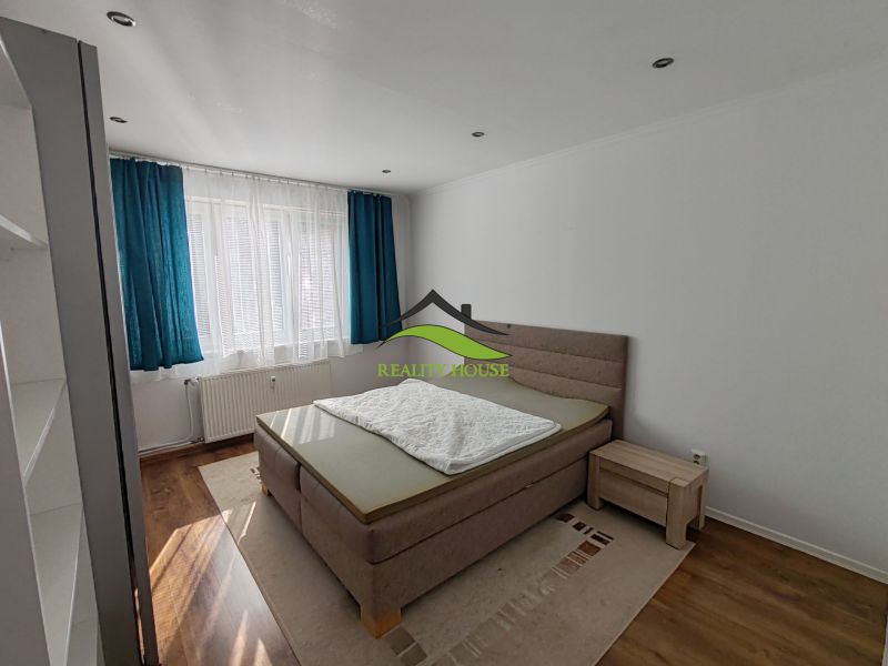 Helles Schlafzimmer in einer 3-Zimmer-Wohnung mit Holzboden und blauen Vorhängen.