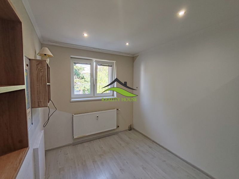 Ein Zimmer in einer 3-Zimmer-Wohnung mit einem Boden in Holzoptik, einer Wandleuchte und einem Heizkörper.