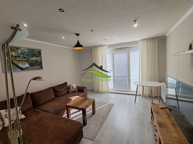Wohnzimmer in einer 3-Zimmer-Wohnung mit Holzboden und braunem Sofa.