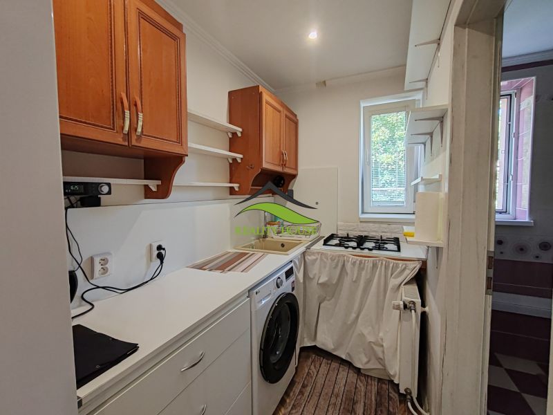 Küche in einer 3-Zimmer-Wohnung mit Holzboden, Waschmaschine und Oberschränken.