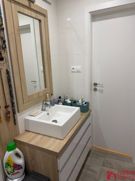 Badezimmer in einer 2-Zimmer-Wohnung mit Waschbecken und Möbeln in Holzoptik.