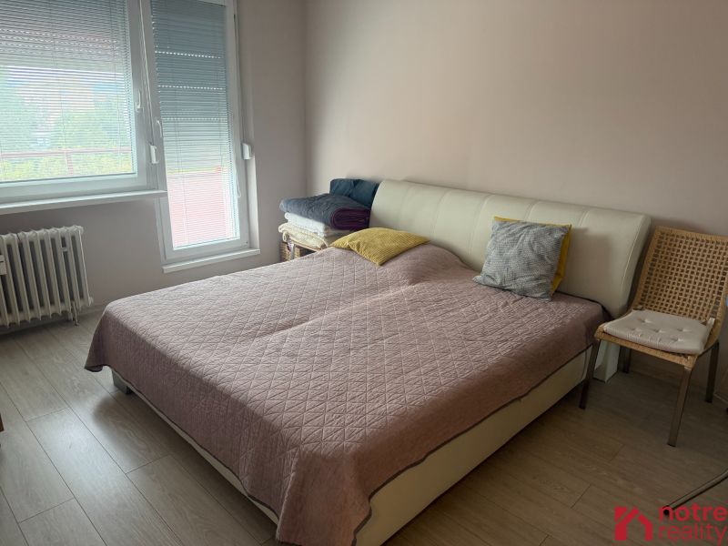 Schlafzimmer mit Bett, Holzboden-Dekor und Sessel in einer 2-Zimmer-Wohnung.