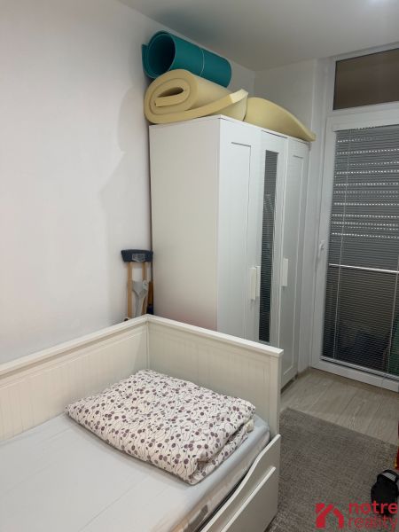 Ein Zimmer mit Bett, Kleiderschrank und zusammengerollten Matratzen in einer 2-Zimmer-Wohnung.