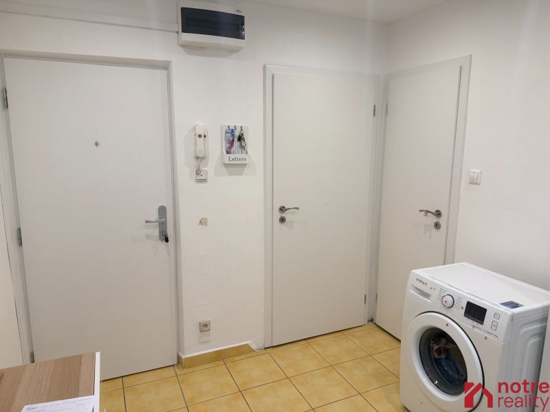 Eingangsflur in einer Zweizimmerwohnung mit gelben Fliesen und Waschmaschine.