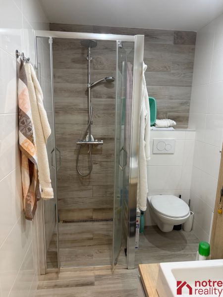 Badezimmer in einer 2-Zimmer-Wohnung mit Holzboden und Duschkabine.