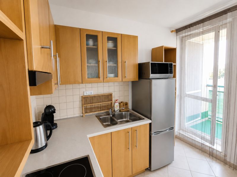 Küche mit Holzschränken, Kühlschrank und Mikrowelle in einer Zweizimmerwohnung.