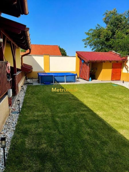 Der Garten eines Einfamilienhauses in Darnózseli mit Rasen und Pool, umgeben von einem Zaun.