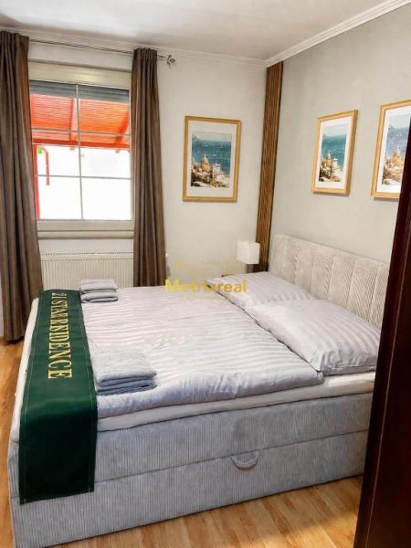 Helles Schlafzimmer in einem Einfamilienhaus mit großem Bett und Boden in Holzoptik.