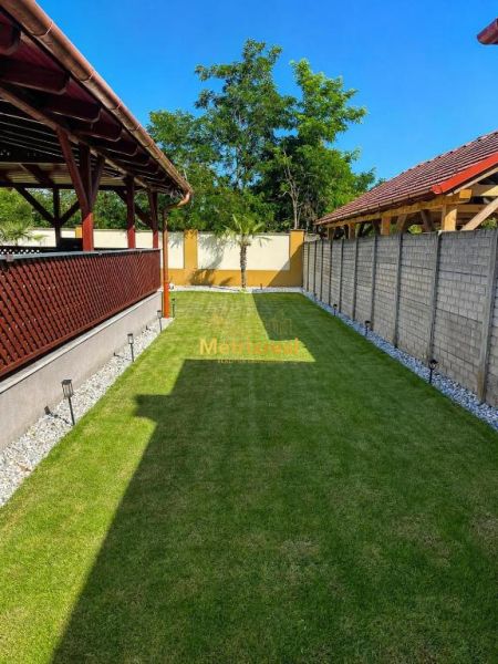 Der Garten eines Einfamilienhauses in Darnózseli mit Rasen, Pergola und von Bäumen umgeben.