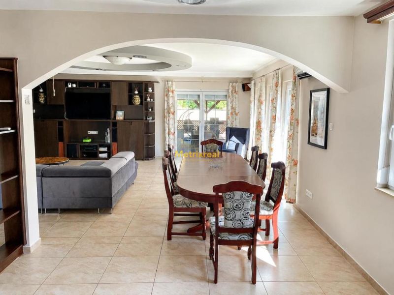 Esstisch und Sofa in einem hellen Interieur eines Einfamilienhauses mit Fliesenboden.
