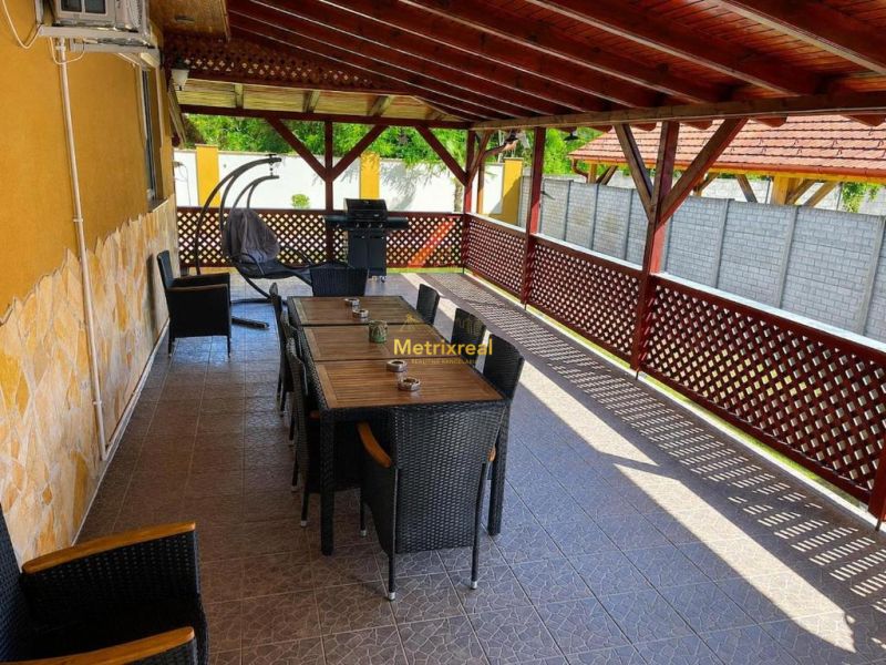 Eine gedeckte Terrasse eines Einfamilienhauses in Darnózseli mit Grill und bequemen Sitzgelegenheiten.