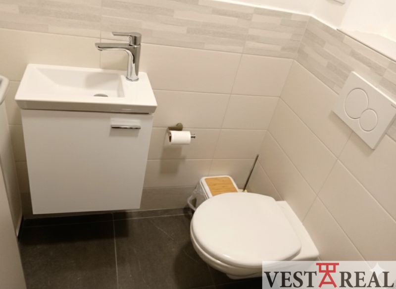 Badezimmer im Büro mit Waschbecken, Toilette und Wandverkleidung.