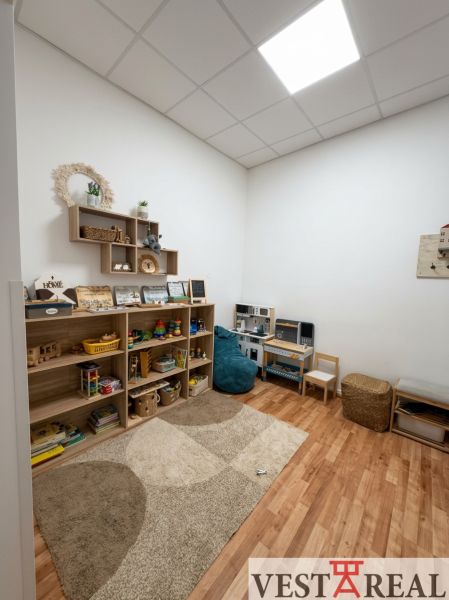 Kinderecke im Büro mit Regalen voller Spielzeug, Boden mit Holzdekor.