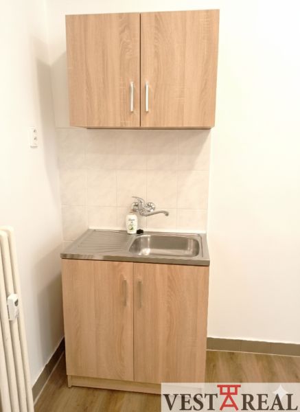 Kleine Küchenzeile mit Spüle und Schränken, Boden mit Holzdekor.