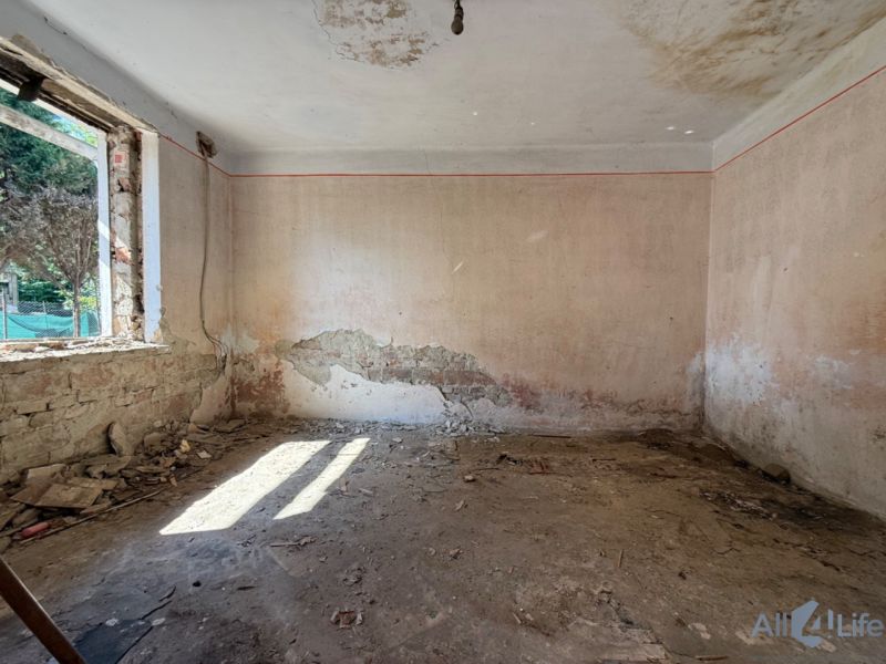 Verlassener Raum mit beschädigten Wänden und einem Fenster in einem Einfamilienhaus.