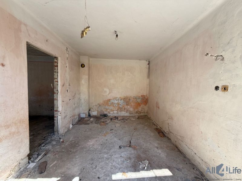 Ein Zimmer in einem Einfamilienhaus vor der Renovierung mit freiliegenden Wänden und Boden.