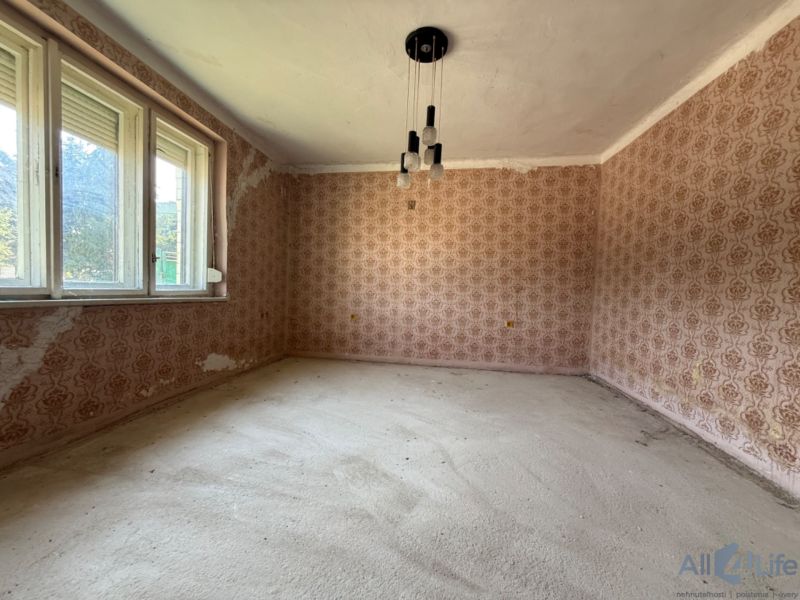 Ein Zimmer in einem Einfamilienhaus mit Blumen-Tapete und großen Fenstern.