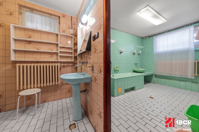 Ein Badezimmer in einem Einfamilienhaus mit grünen Fliesen und einem blauen Waschbecken, Retro-Design.