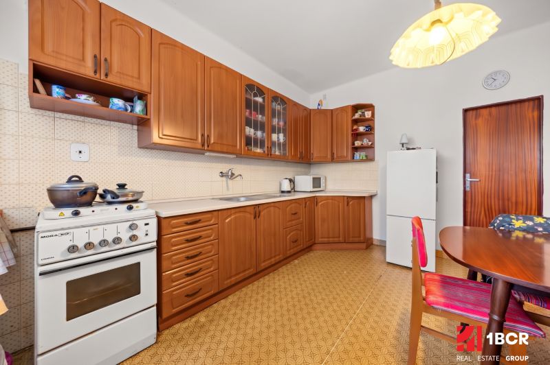 Küche in einem Einfamilienhaus mit Holzschränken, Herd und Esstisch.