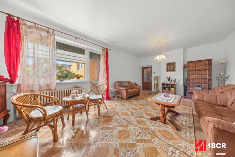 Wohnzimmer in einem Einfamilienhaus mit bequemen Möbeln und einem Boden in Holzoptik.