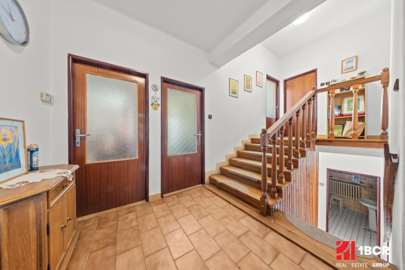 Der Flur eines Einfamilienhauses mit einem Holzgeländer und Dekorationen an den Wänden.