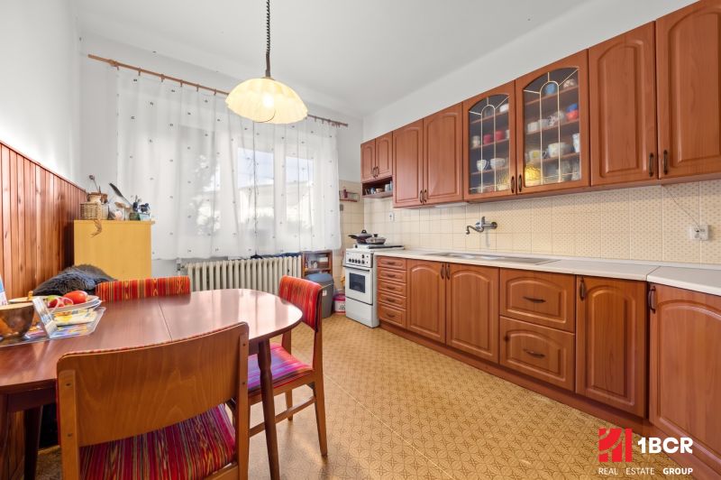 Eine Küche in einem Einfamilienhaus mit Holzmöbeldekor und Vorhängen an den Fenstern.