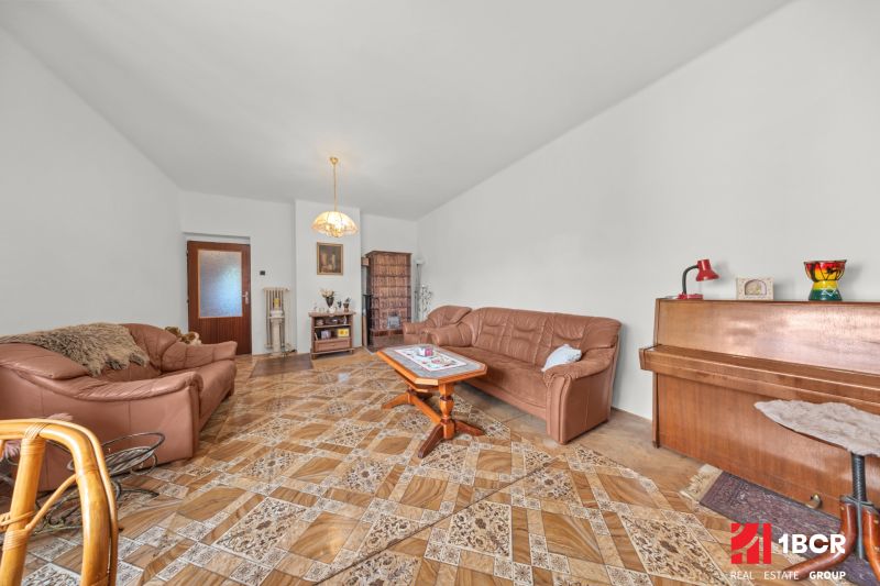 Wohnzimmer in einem Einfamilienhaus mit Ledersofa, Klavier und Holzboden.