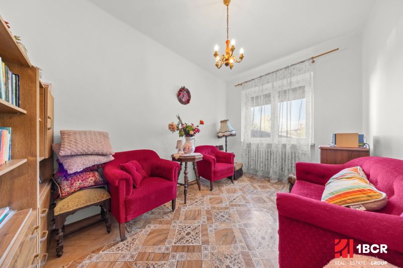 Wohnzimmer in einem Einfamilienhaus mit roten Sesseln und einem Tisch auf einem Boden mit Holzdekor.
