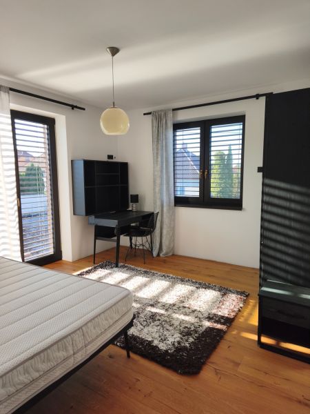 Schlafzimmer im Einfamilienhaus mit Holzboden, Schreibtisch und Teppich.