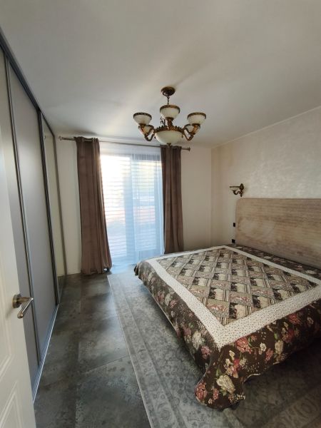 Ein Schlafzimmer in einem Einfamilienhaus mit einem großen Bett, Schränken und einem eleganten Kronleuchter.