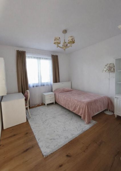 Schlafzimmer in einem Einfamilienhaus mit Bett, Schreibtisch und Boden mit Holzdekor.